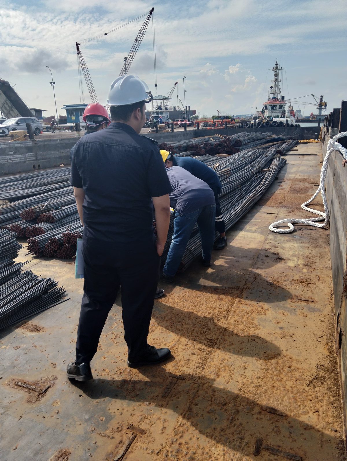 Crew standing and reviewing rebar cargo at the dock